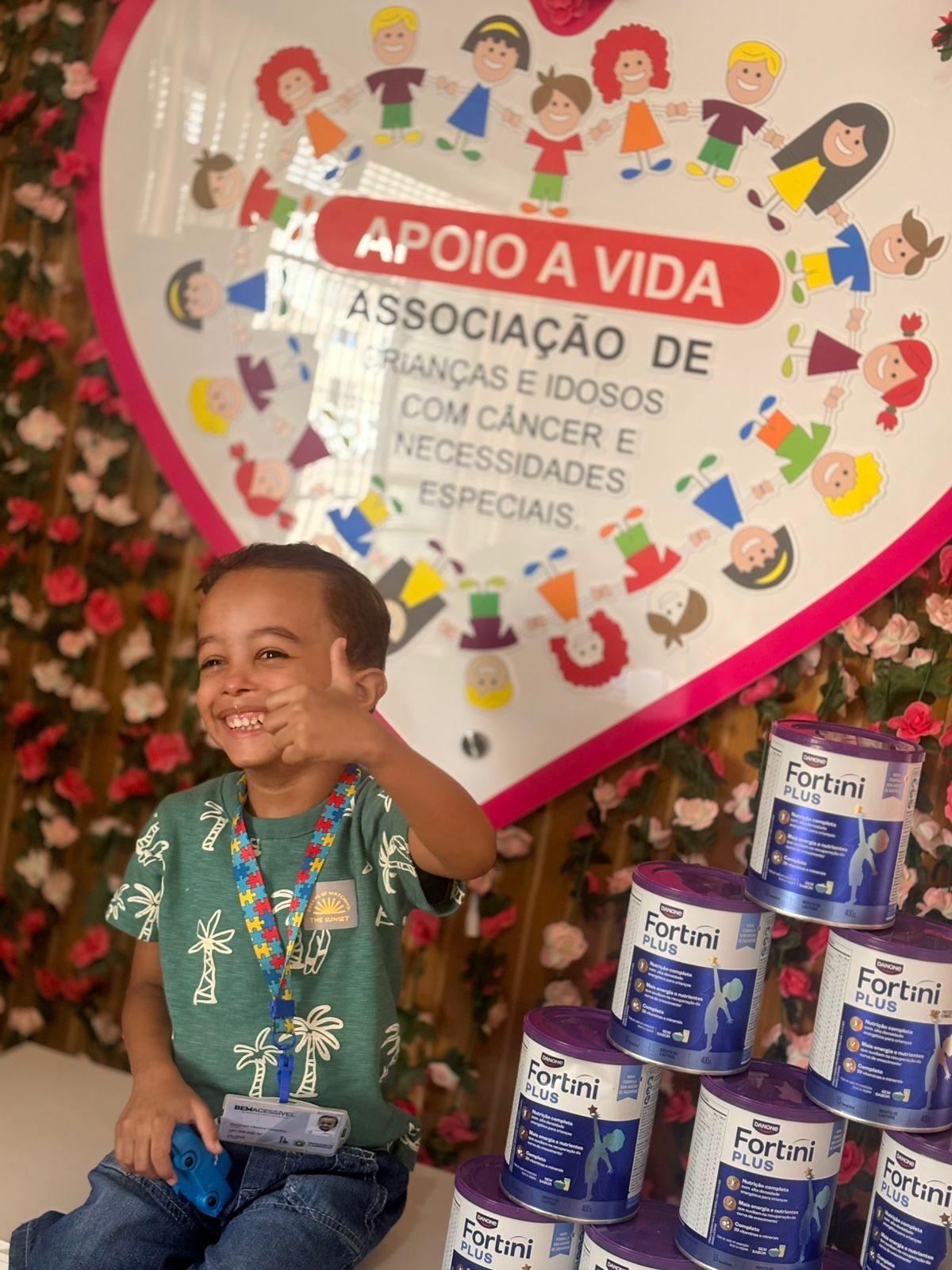 Criança atendida pela Apoio à Vida sorrindo em frente ao painel da instituição