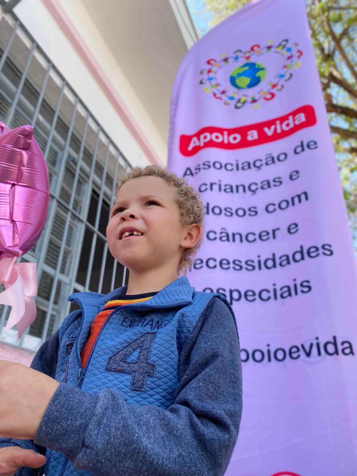 Criança em ação externa com o banner da Apoio à Vida